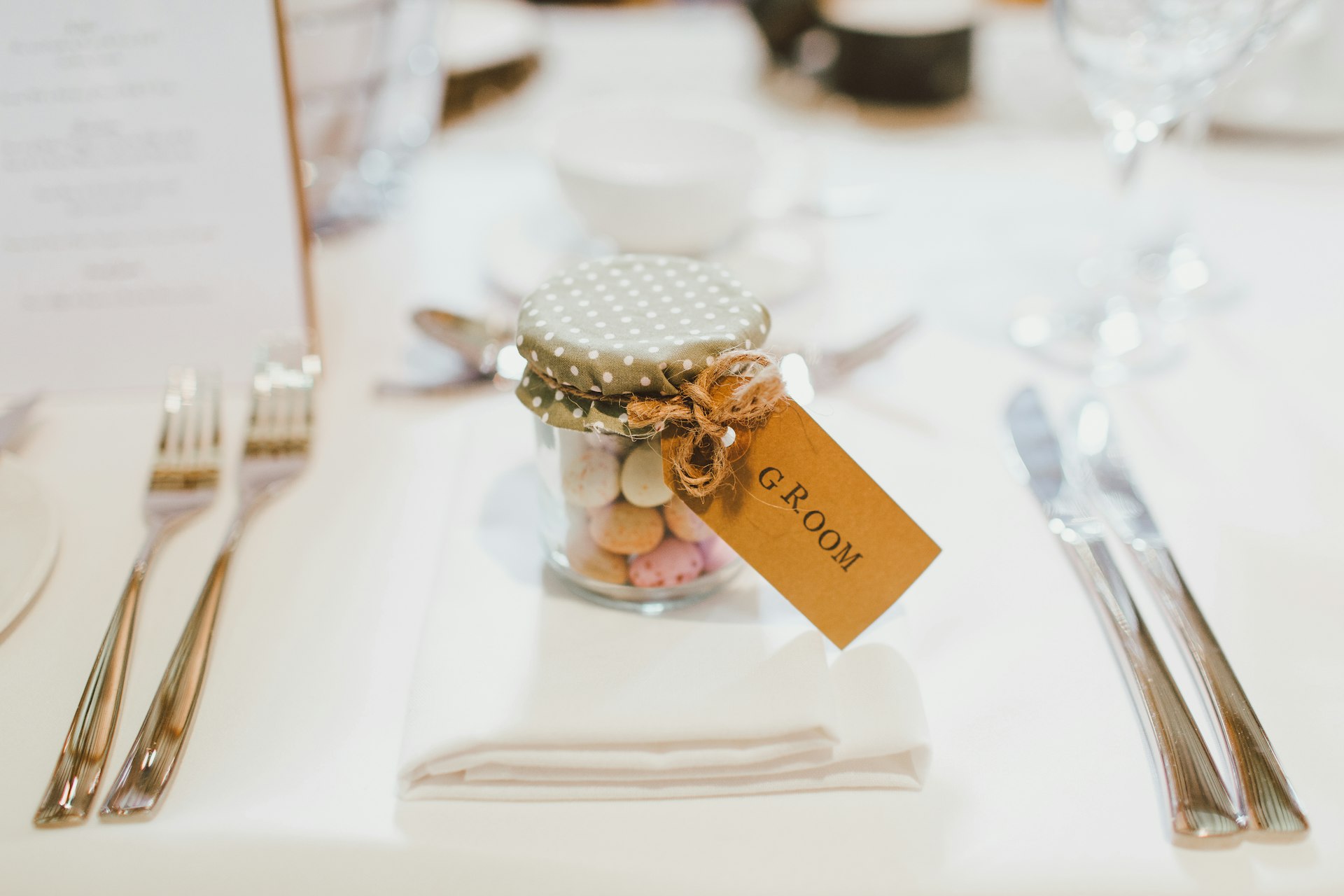 clear glass mason jar on top of white table napkin between forks and knives